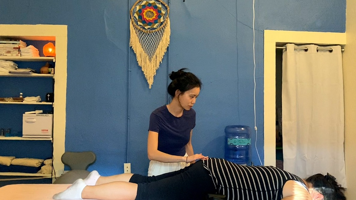 Eleanor giving a gentle Spinal Flow session to a fully clothed client resting on the table